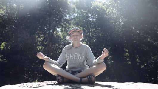 Young girl sitting on a rock cross-legged, in the South Downs National Park.